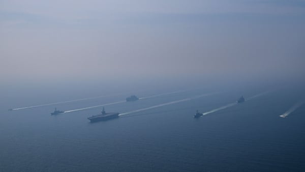 An aerial view of the USS Abraham Lincoln Carrier Strike Group while operating at the Arabian Sea, escorted by two military replenishment ships and two U.S. Coast Guard vessels