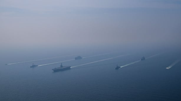 An aerial view of the USS Abraham Lincoln Carrier Strike Group while operating at the Arabian Sea, escorted by two military replenishment ships and two U.S. Coast Guard vessels