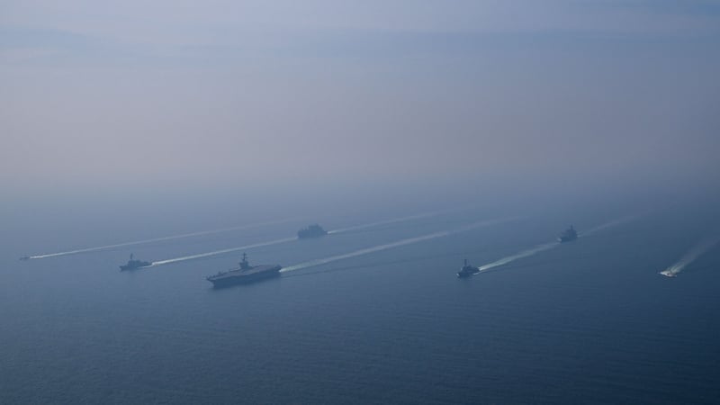 An aerial view of the USS Abraham Lincoln Carrier Strike Group while operating at the Arabian Sea, escorted by two military replenishment ships and two U.S. Coast Guard vessels