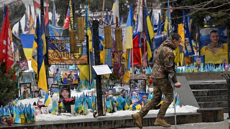 A wounded Ukrainian serviceman walks past makeshift memorial for fallen soliders
