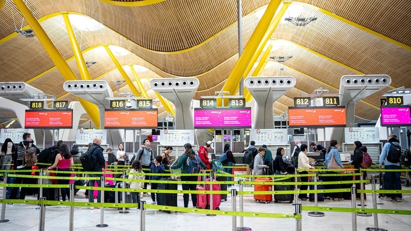 Travelers at an airport line up to check in