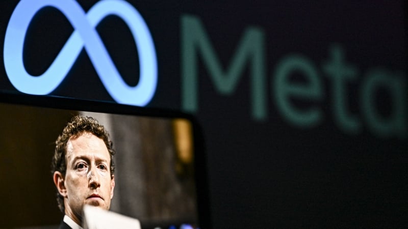 A computer screen displays Meta logo and a mobile phone screen displays founder of Meta Mark Elliot Zuckerberg in the foreground