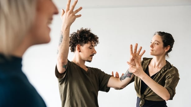 Female mature teacher in a dancing studio correcting one of her male dancers