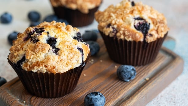 Cupcakes (muffins) with blueberries and streusel (confectionery crumbs) on a wooden stand. A delicious summer dessert for morning tea or breakfast.