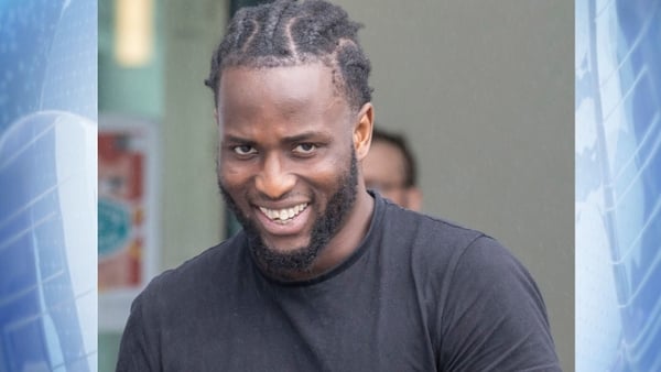 Adeleke Adelani looking to camera on a blue background