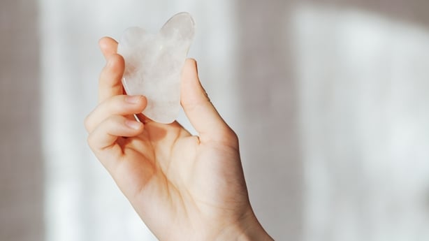 Hand holding stone massager against light background.