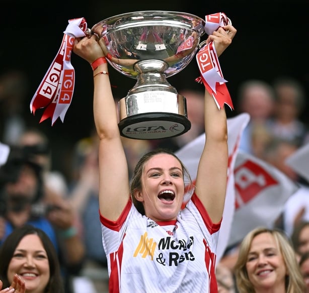 3 August 2025; Tyrone captain Aoibhinn McHugh lifts the Mary Quinn Memorial cup, alongside Uachtarán Cumann Peil Gael na mBan, Trina Murray, left, after the TG4 All-Ireland Ladies Football Intermediate Championship final match between Laois and Tyrone at Croke Park in Dublin. Photo by Shauna Clinton