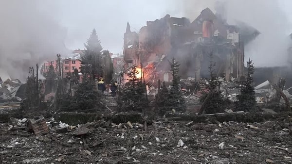 Fire engulfs a building with tree in the foreground
