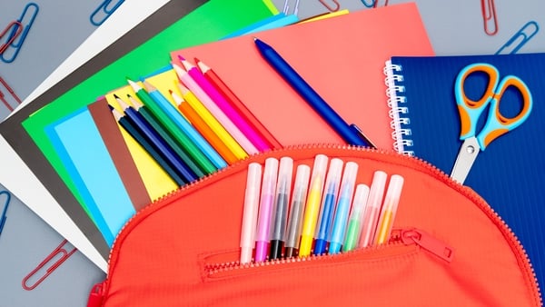 colourful pens and pencils with school notebooks displayed on a table