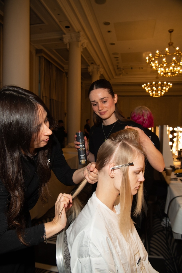 A number of hairdressers working on a model's hair back stage