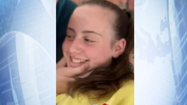 close up of Mia Lily Keogh O Keeffe with a hand over her chin against a blue background