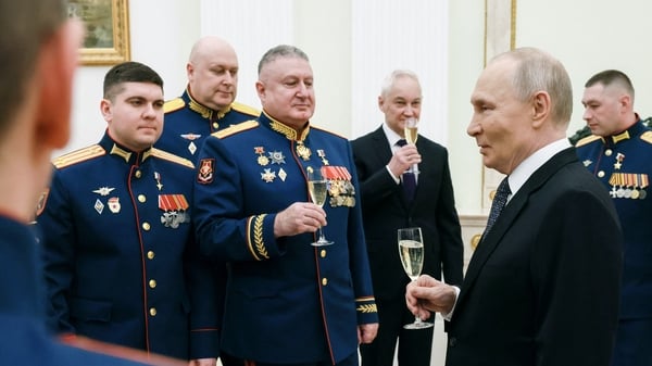 In this pool photograph distributed by the Russian state agency Sputnik, Russia's President Vladimir Putin (2nd-R) makes a toast with servicemen awarded with Gold Star medals of 'Hero of Russia' during a ceremony on Defender of the Fatherland Day in Mosco