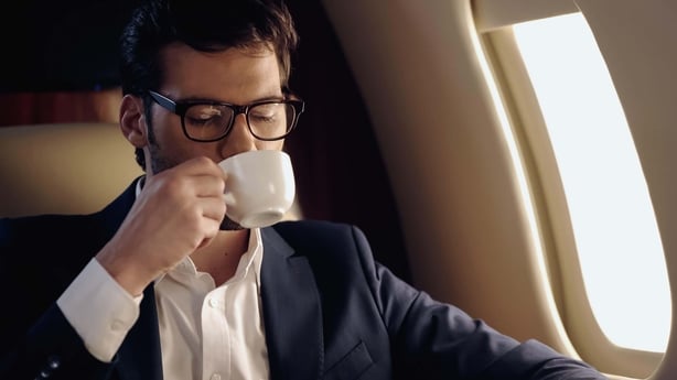 A man drinking coffee on a flight