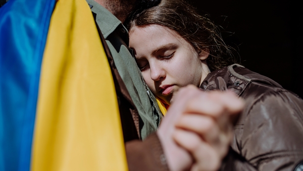 A daughter hugs her fagther with Ukrainian flag in foreground