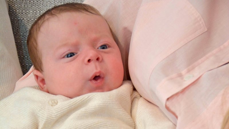 a small baby held in his mother's arms