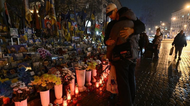 A couple embrace in front of a makeshift memorial for Ukrainian and foreign soldiers during at Independence Square in Kyiv
