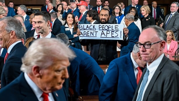 Representative Al Green holds a "Black People Aren't Apes" sign as Donald Trump arrives at State of Union address