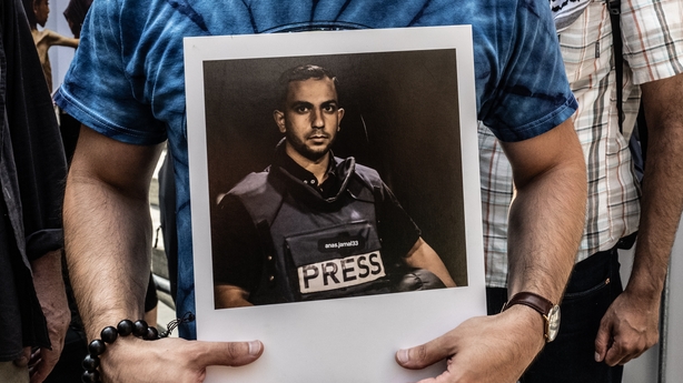 A person holds a photo of slain Al Jazeera journalist Anas al-Sharif at a protest