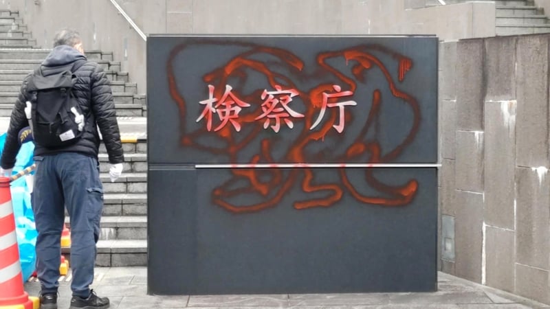 Photo shows a sign reading "Prosecutor's Office" in front of the Osaka Nakanoshima Joint Government Building defaced with what appears to be red spray paint