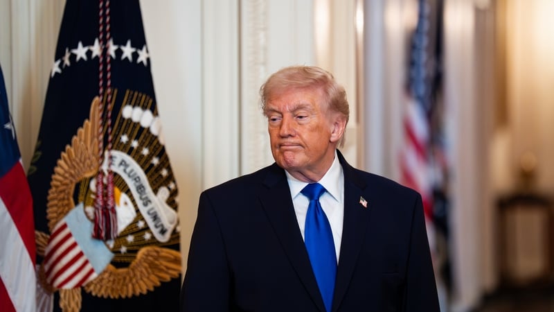 a photograph of US President Donald Trump standing beside a flag