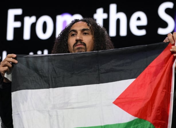 Syrian-Palestinian director Abdallah Al-Khatib stands on stage with a Palestinian flag as he accepts the GWFF Best Feature Film Debut Award for Chronicles from the Siege during the awards ceremony of the 76th Berlinale in Berlin on 21 February, 2026 (Photo by RALF HIRSCHBERGER / AFP)