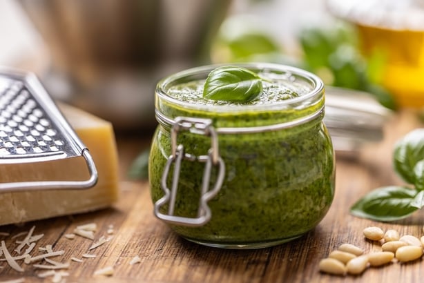 Basil pesto in a jar and other ingredients for preparation around it. Basil leaves, pine nuts, parmesan and salt. Basil pesto, often just called pesto, is a traditional Italian sauce originating from Genoa, the capital of Liguria.