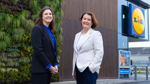 Two female AIB and Lidl business leaders stand outside a Lidl store