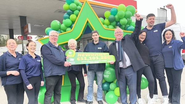 People celebrate the sale of a winning lottery ticket in Co Mayor shop with green balloons and props