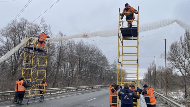Municipal workers erect anti-drone nets on a road leading from Kharkiv to the Russian border