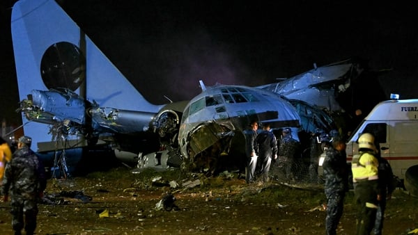 Police stand next to the wreckage of a plane crash
