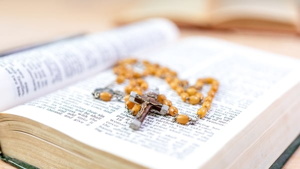 Closeup of wooden Christian cross necklace next to holy Bible