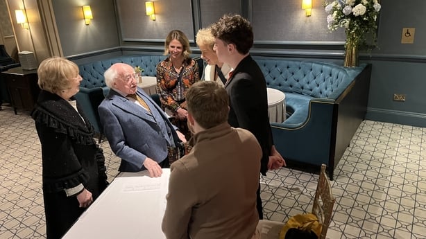 Former president Michael D Higgins and his wife Sabina greet a group of people in a function room.