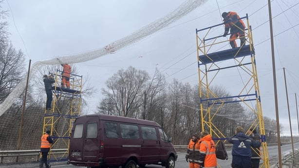 Construction workers lay anti-drone nets on a road on the outskirts of Kharkiv