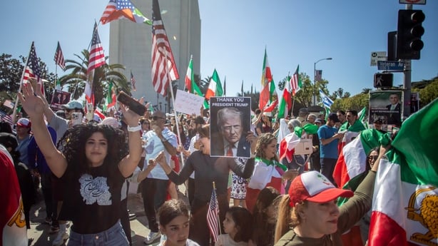 A woman holds a portrait of US President Donald Trump reading "thank you" as people wave US and Iranian pre-1979 Islamic Revolution flags as members of the Iranian community celebrate in front of the Federal Building in the West LA neighborhood of Los Angeles