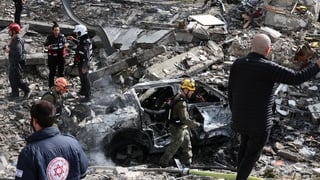 An Israeli emergency service officer walks past the debris of building at the scene of a missile attack near Bet Shemesh