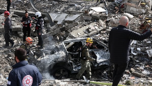An Israeli emergency service officer walks past the debris of building at the scene of a missile attack near Bet Shemesh