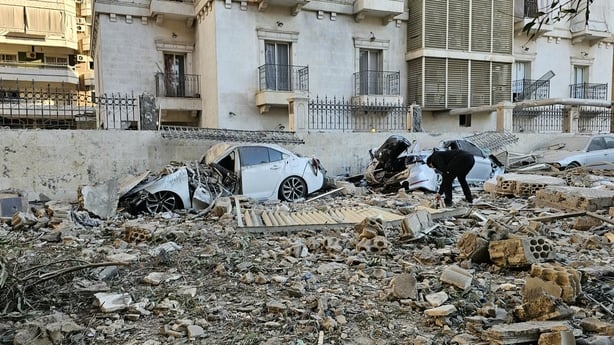 A man is seen checking wreckage of cars and buildings after an air strike on Beirut