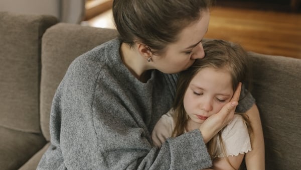Mother kissing sad daughter at home