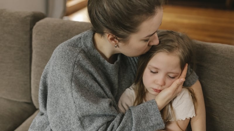 Mother kissing sad daughter at home