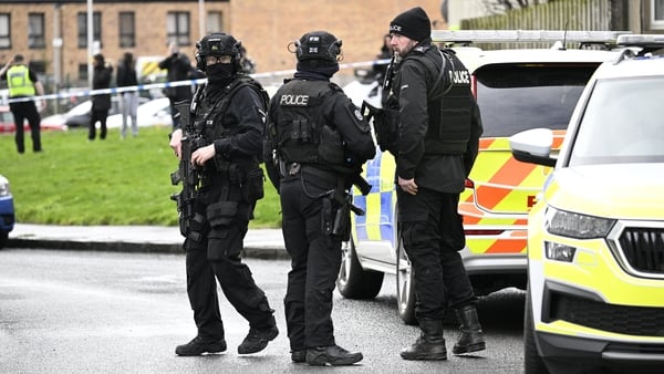 Police at the scene in Calder, Edinburgh, in riot gear beside police vehicles with people in background