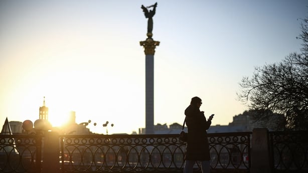 A woman stands in Independence Square at sunset as temperatures rise above freezing, in Kyiv on 1 March