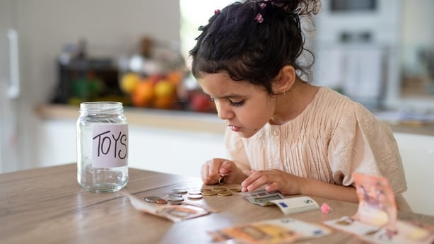 Little multiracial girl saving her money in to jar for toys.