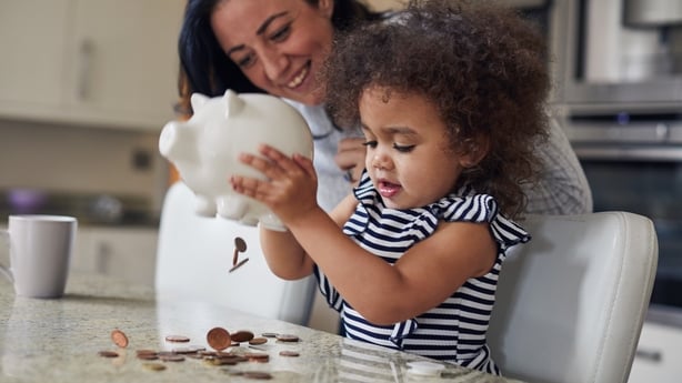 Mother and toddler girl getting money out of a piggy bank