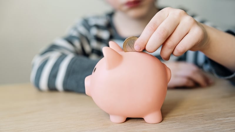 A boy putting a coin into a piggy bank