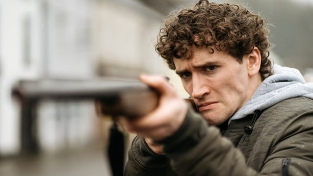 Art Parkinson as Éamonn points a gun in Aontas