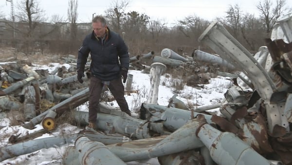 Tony Connelly climbs over used drones at the the so-called drone cemetery in Kharkiv