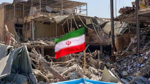 An Iranian flag is placed amid rubble and debris