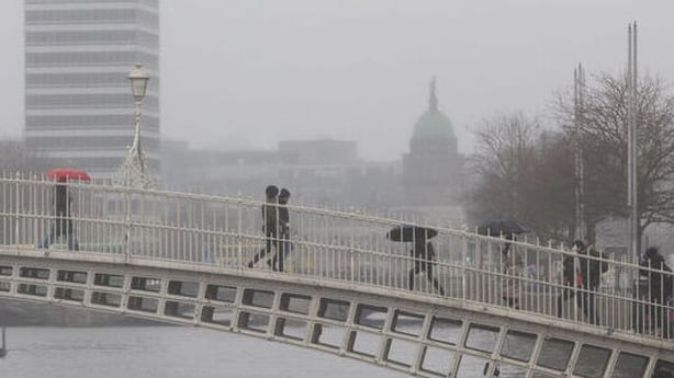 People are seen walking across the Ha'penny Bridge while it's raining in Dublin