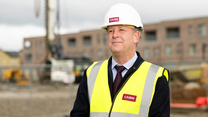 Image of a business man in a hardhat and high-vis jacket on a building site