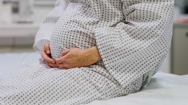 stock image of a pregnant woman wearing a hospital gown 